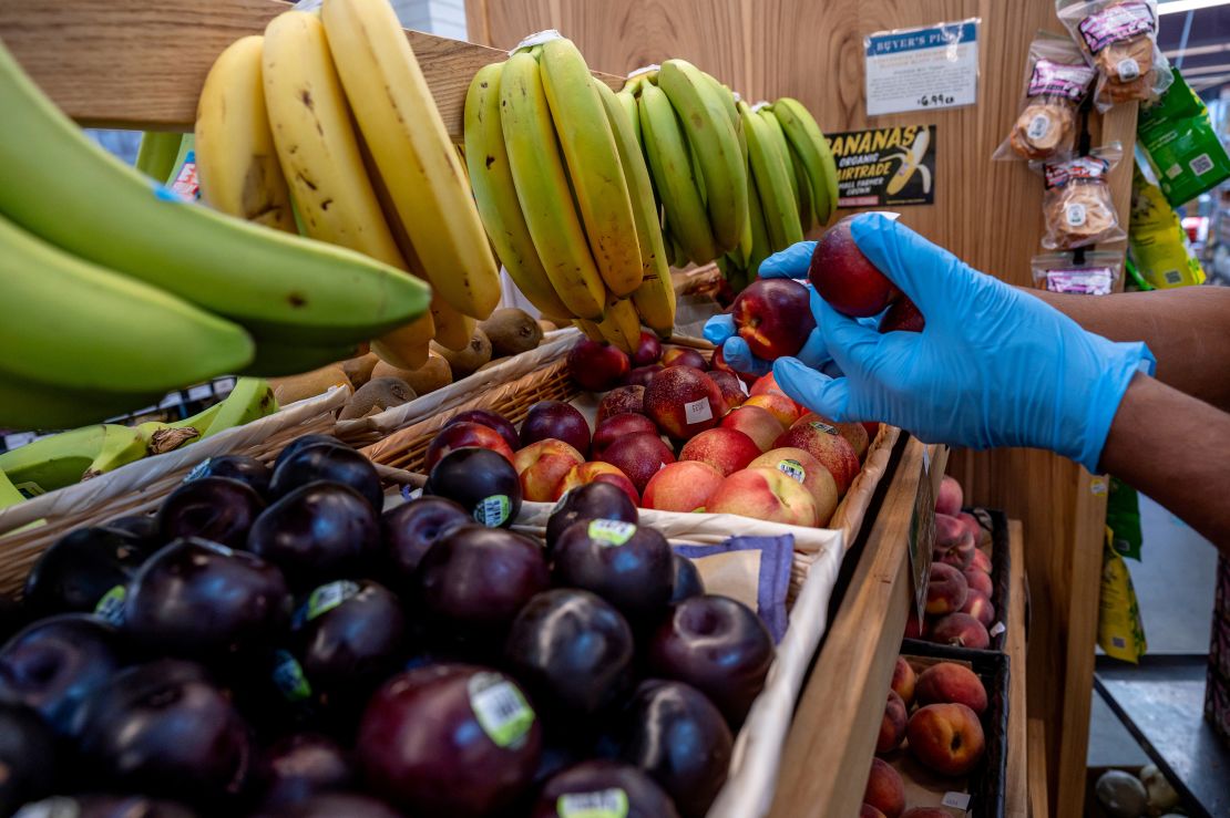 A worker stocks produce at a grocery store in San Francisco.