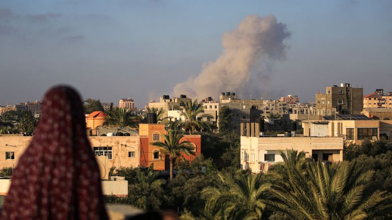 A Palestinian woman watches as smoke billows following an Israeli strike south of Gaza City, in the town of al-Zawaida in the central Gaza Strip, on June 11, 2024.