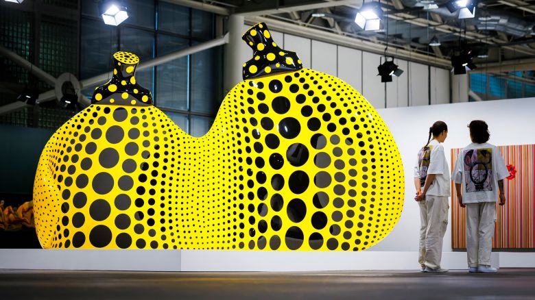Art Basel's staff members stand next to by "Aspiring to Pumpkin's Love, the Love in My Heart" 2023, by Japanese artist Yayoi Kusama displayed at the Unlimited sector of Art Basel fair for Modern and contemporary art, in Basel, northern Switzerland, on June 11, 2024. (Photo by Valentin FLAURAUD / AFP) / RESTRICTED TO EDITORIAL USE - MANDATORY MENTION OF THE ARTIST UPON PUBLICATION - TO ILLUSTRATE THE EVENT AS SPECIFIED IN THE CAPTION (Photo by VALENTIN FLAURAUD/AFP via Getty Images)