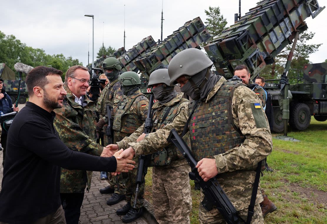 El presidente de Ucrania, Volodymyr Zelensky, y el ministro de Defensa alemán, Boris Pistorius, saludan a soldados alemanes y ucranianos que se entrenan en el uso de sistemas Patriot en una zona de entrenamiento en Alemania.
