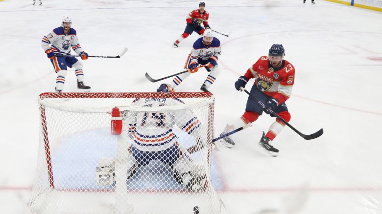 Carter Verhaeghe of the Florida Panthers, in red, scores a goal against the Edmonton Oilers during Game 1 of the 2024 Stanley Cup Final at Amerant Bank Arena in Sunrise, Florida, on Saturday.