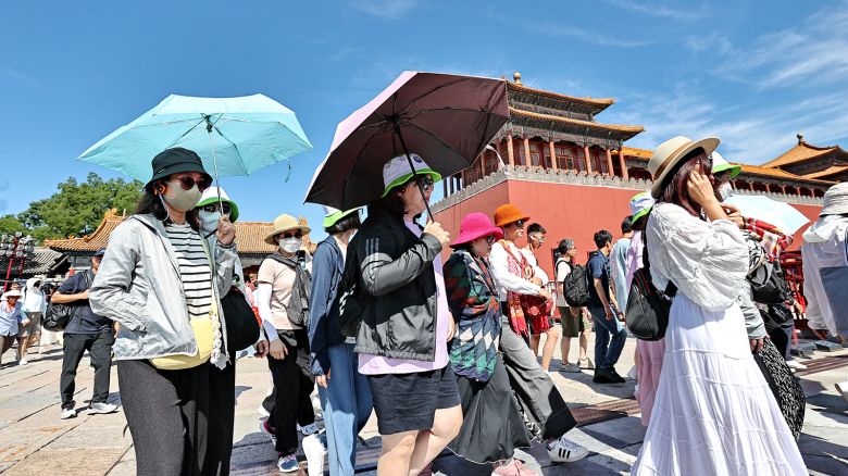 Tourists shield themselves from the sunshine while visiting the Palace Museum during the Dragon Boat Festival holiday on June 9, 2024 in Beijing, China. Beijing Meteorological Observatory issued the first yellow alert for high temperatures in 2024, with the highest temperature in the city reaching 35 degrees Celsius.