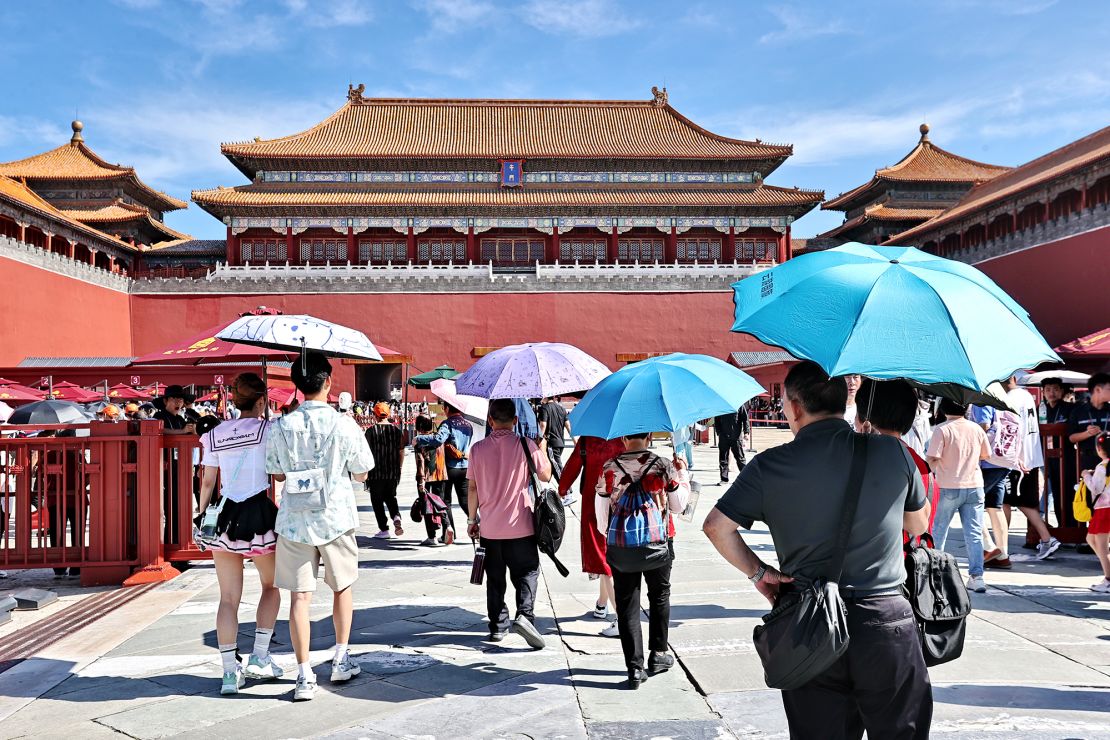 Tourists shield themselves from the sunshine while visiting the Palace Museum during the Dragon Boat Festival holiday on June 9, 2024 in Beijing, China. Beijing Meteorological Observatory issued the first yellow alert for high temperatures in 2024, with the highest temperature in the city reaching 35 degrees Celsius.