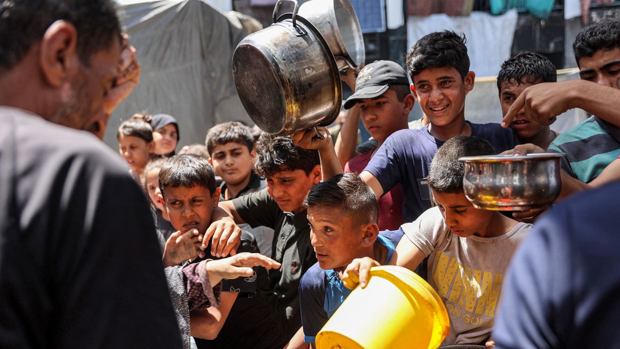 Children queue with pots to receive food aid from a kitchen at the Abu Zeitun school run by the UN Relief and Works Agency for Palestine Refugees (UNRWA) in the Jabalia camp for Palestinian refugees in the northern Gaza Strip on June 13, 2024 amid the ongoing conflict in the Palestinian territory between Israel and Hamas. (Photo by Omar AL-QATTAA / AFP) (Photo by OMAR AL-QATTAA/AFP via Getty Images)