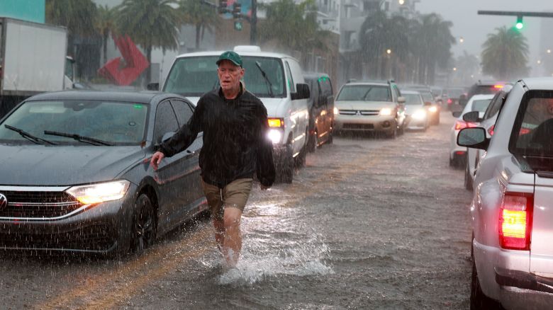 HALLANDALE BEACH, FLORIDA - JUNE 12: A person walks through a flooded street on June 12, 2024, in Hallandale Beach, Florida. As tropical moisture passes through the area, the streets have become flooded due to the heavy rain. (Photo by Joe Raedle/Getty Images)