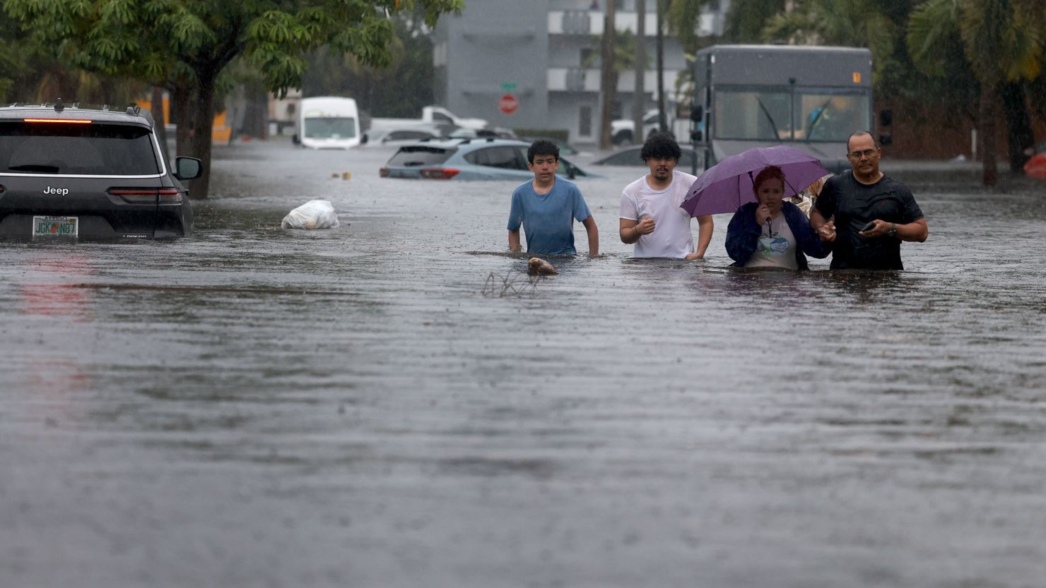 People navigate a flooded street as they evacuate on June 12, 2024, in Hollywood, Florida.