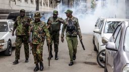 Kenya police officers walk away from a street covered on tear gas during a demonstration against tax hikes on June 18, 2024.