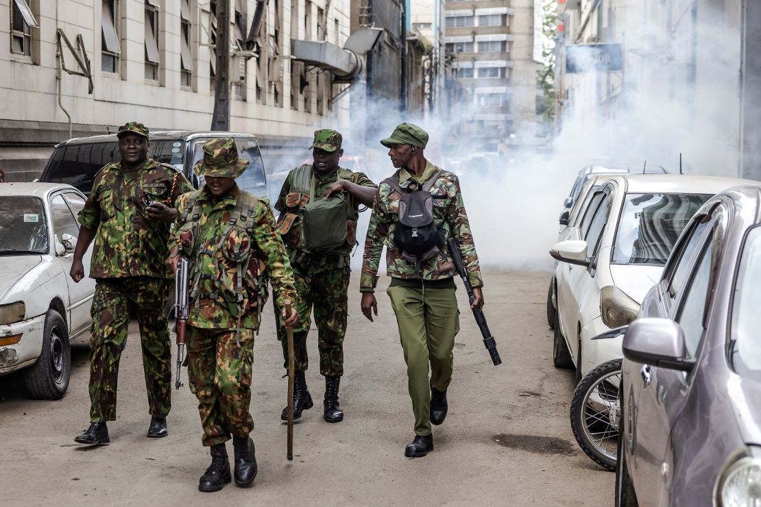 Kenyan police officers walk away from a street covered in tear gas during a demonstration against tax hikes in downtown Nairobi on June 18, 2024.