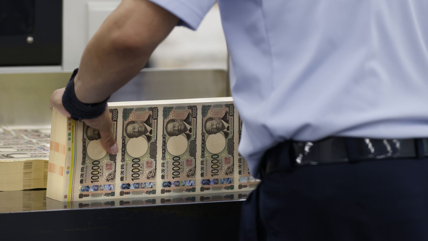 An employee handles sheets of newly-designed Japanese 10,000-yen banknotes at the National Printing Bureau's Tokyo plant on June 19, 2024.