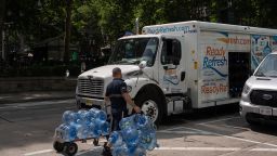A worker wheels empty water jugs to a truck during high temperatures in New York, US, on Thursday, June 20, 2024.