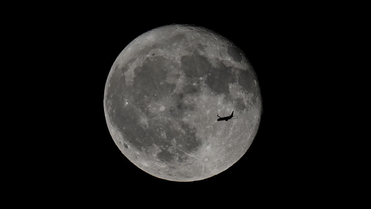 FOSTER CITY, CALIFORNIA - JUNE 22: A passenger plane flies in front of the full 'strawberry' moon over San Francisco Bay as seen from Foster City in California, United States on June 22, 2024. (Photo by Tayfun Coskun/Anadolu via Getty Images)