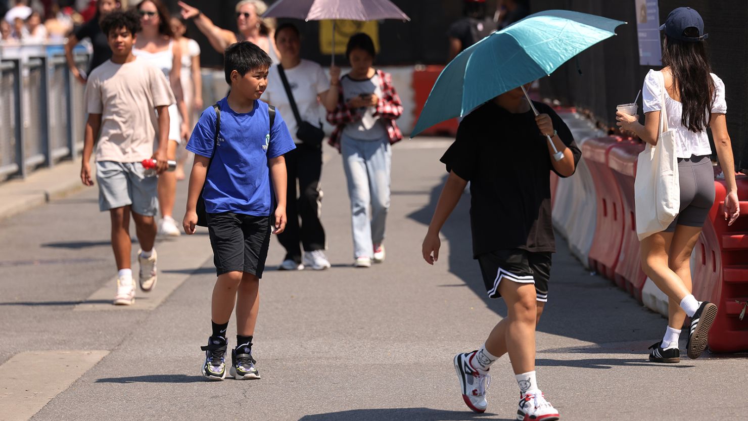 People walk along Brooklyn Bridge Park amid a heat wave on June 19, 2024, in the Brooklyn borough in New York City.