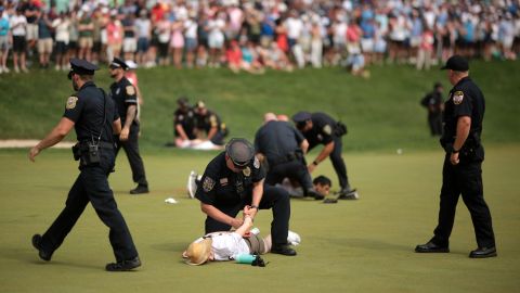 CROMWELL, CONNECTICUT - JUNE 23: Climate change protestors are ushered off the 18th green by police officers during the final round of the Travelers Championship at TPC River Highlands on June 23, 2024 in Cromwell, Connecticut. (Photo by James Gilbert/Getty Images)