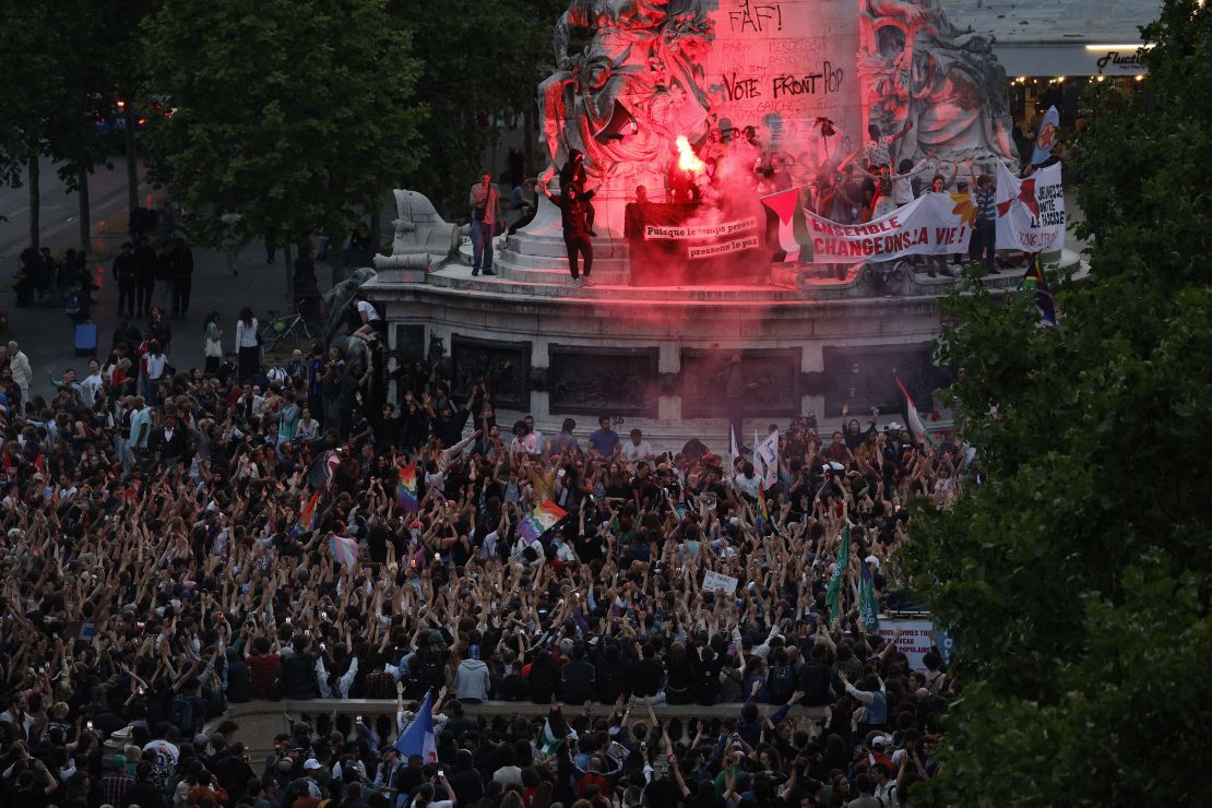 Demonstrators standing on the Monument a la Republique light flares as they take part in a rally after the announcement of the results of the first round of French parliamentary elections, at Place de la Republique in Paris on June 30, 2024.