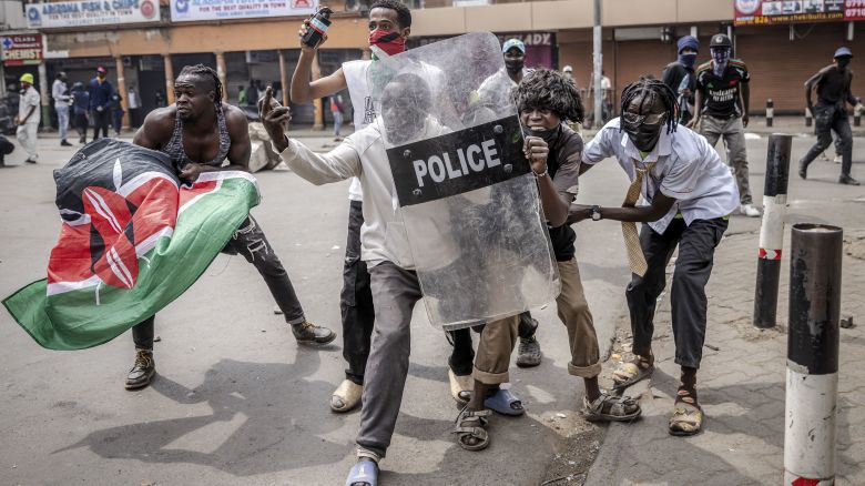 Protesters use a Kenya Police anti-riot shield to protect themselves from tear gas canisters and rubber bullets during anti-government demonstrations in downtown Nairobi, on July 2, 2024.