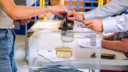 Close-up of the hand of a voter who places his blue envelope containing his ballot in the ballot box in the polling station of the Kergomard nursery school in Valence in the south east of France, June 30, 2024. First round of voting legislative elections.