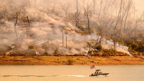 A boat moves along Lake Oroville as the Thompson Fire continues to burn in Oroville, California on July 3, 2024. A heatwave is sending temperatures soaring resulting in red flag fire warnings throughout the state.