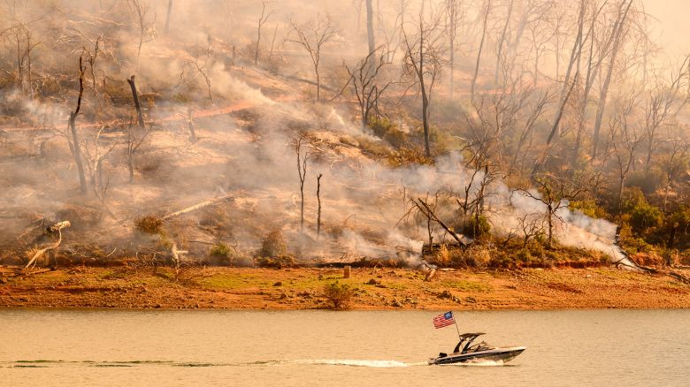 A boat moves along Lake Oroville as the Thompson Fire continues to burn in Oroville, California on July 3, 2024. A heatwave is sending temperatures soaring resulting in red flag fire warnings throughout the state.