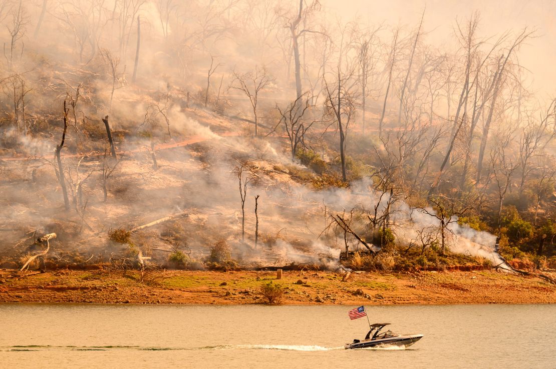 A boat moves along Lake Oroville as the Thompson Fire continues to burn in Oroville, California, on Wednesday.