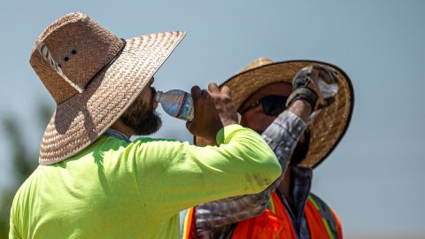 Construction workers drink water in Folsom, California, US, on Wednesday, July 3, 2024. California's biggest power utility had warned of potential outages as the state faces a period of high wildfire risk and power demand surges to keep air conditioners running, with temperatures in Sacramento remaining above 110F (38C) for daytime highs this week, National Weather Service computer models show. Photographer: David Paul Morris/Bloomberg via Getty Images