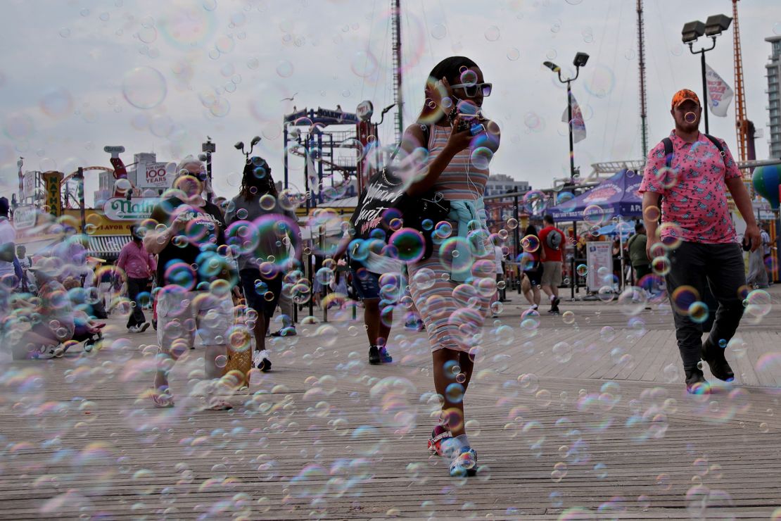 Bubbles float while people stroll on the boardwalk at Coney Island on July 4, 2024.