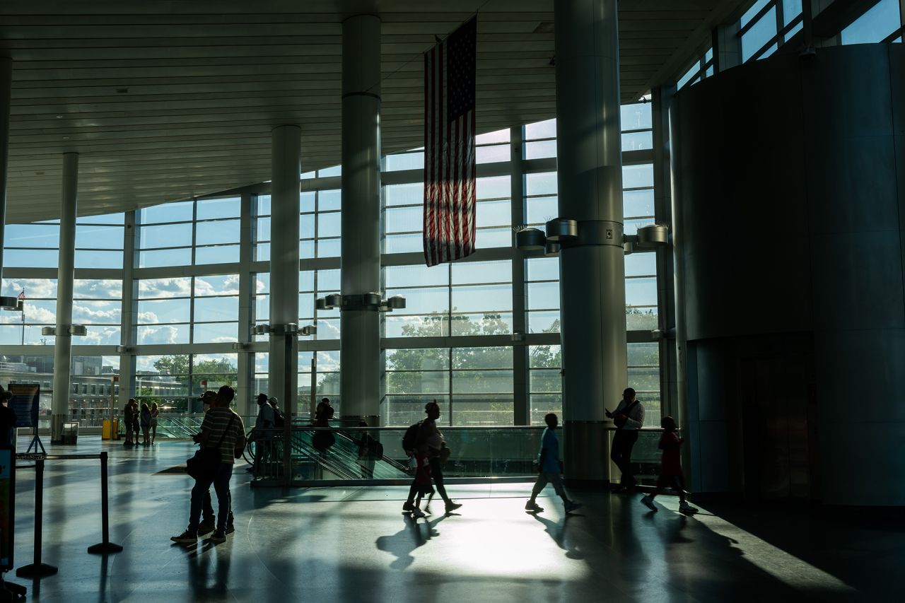 Commuters walk under an American flag at the Staten Island Ferry terminal in Manhattan on July 1 in New York City.