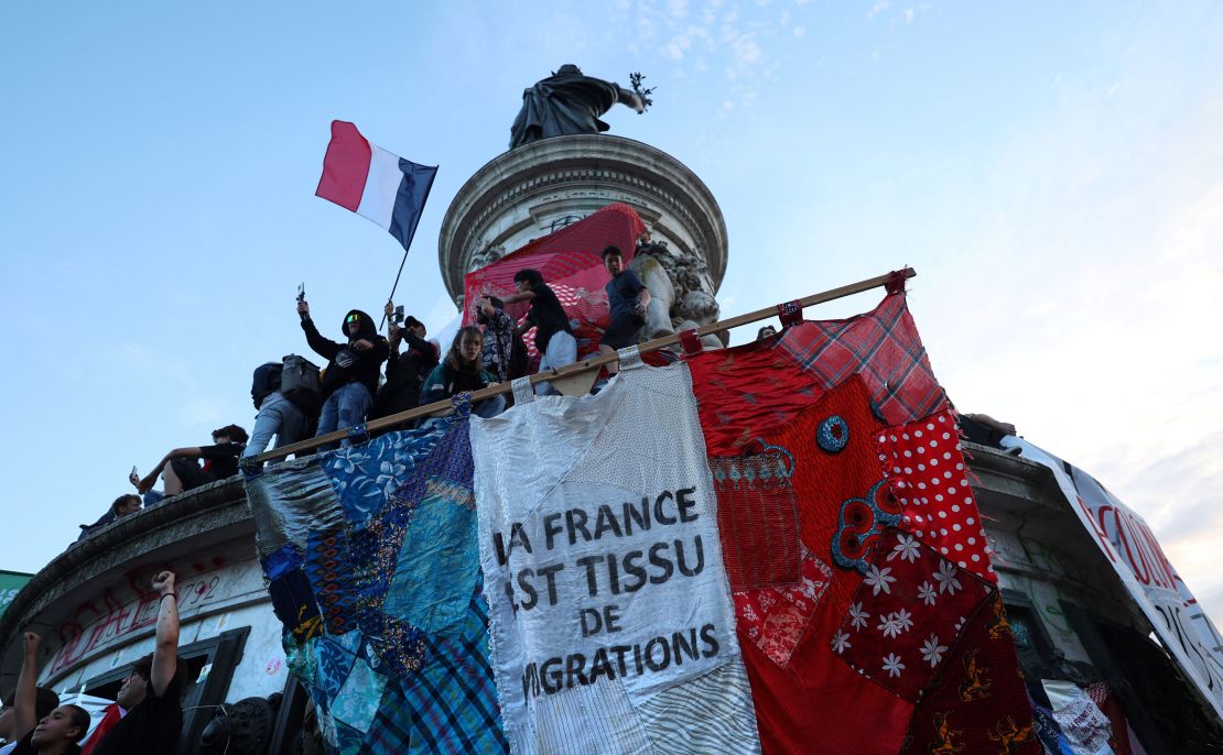 A giant French flag reads "France is born out of migration," at an event in Republique Square in Paris.