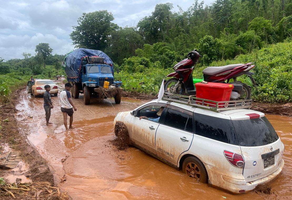 Displaced people fleeing fighting in Lashio try to cross the flooded road to Taunggyi in Myanmar's northern Shan state on July 9, 2024.