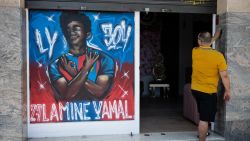 TOPSHOT - A man looks at a graffiti depicting Lamine Yamal in Rocafonda, the neighbourhood where Spain's forward grew up, in Mataro, 35km from Barcelona, on July 11, 2024. Every time he scores a goal, Lamine Yamal usually signs the number 304 with his hands. It is the postal code of the humble Catalan neighborhood where he spent part of his childhood, Rocafonda, which is now very excited about his success and for finally being in the news for good reasons. (Photo by Josep LAGO / AFP) (Photo by JOSEP LAGO/AFP via Getty Images)