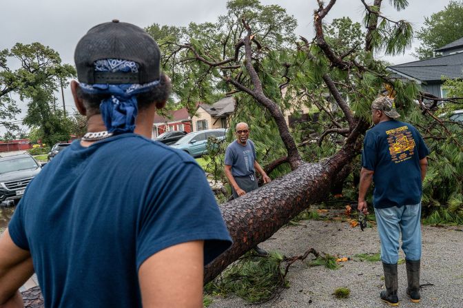 Houston residents assess a fallen tree in their neighborhood after Hurricane Beryl swept through the area on Monday.