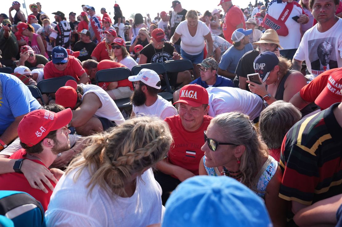 Members of the crowd duck under chairs after Donald Trump is assisted offstage during a campaign rally on Saturday, July 13, in Butler, Pennsylvania.