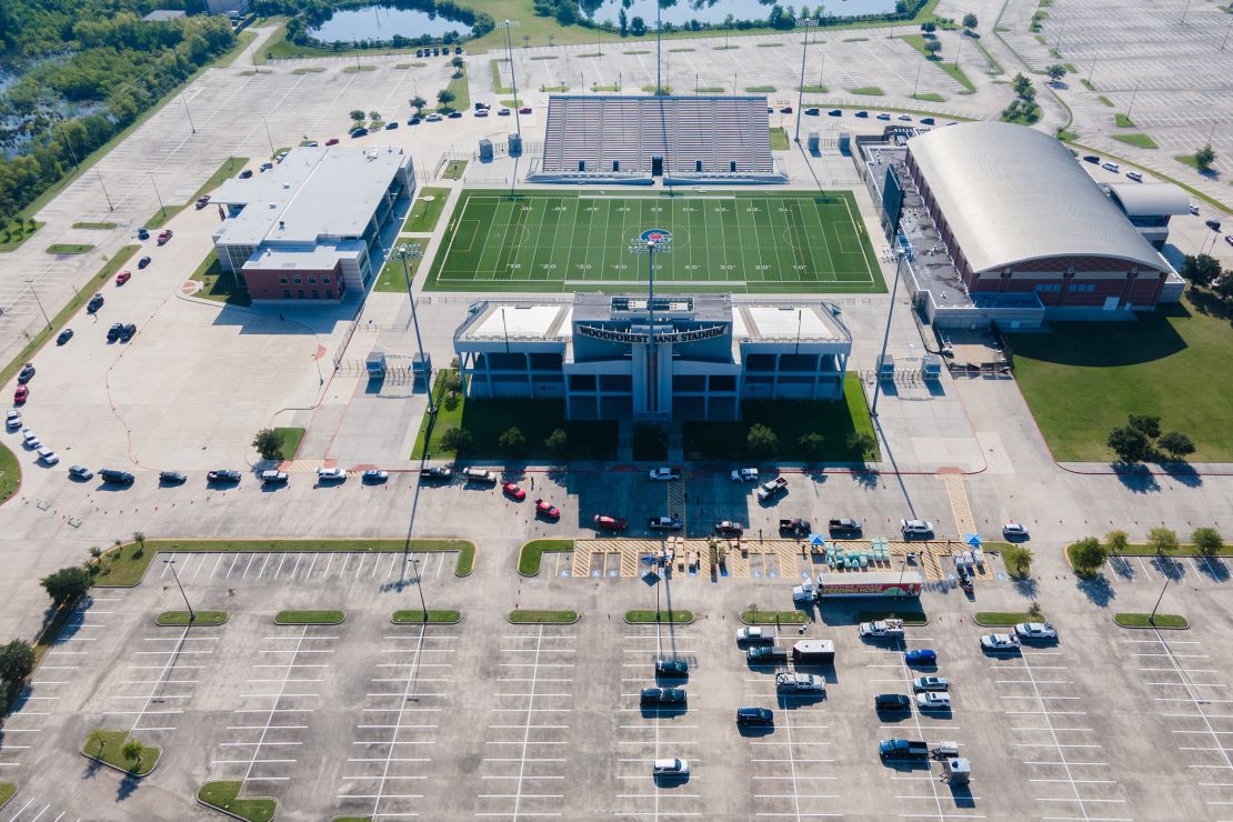 An aerial view of cars lined up around the a football stadium.