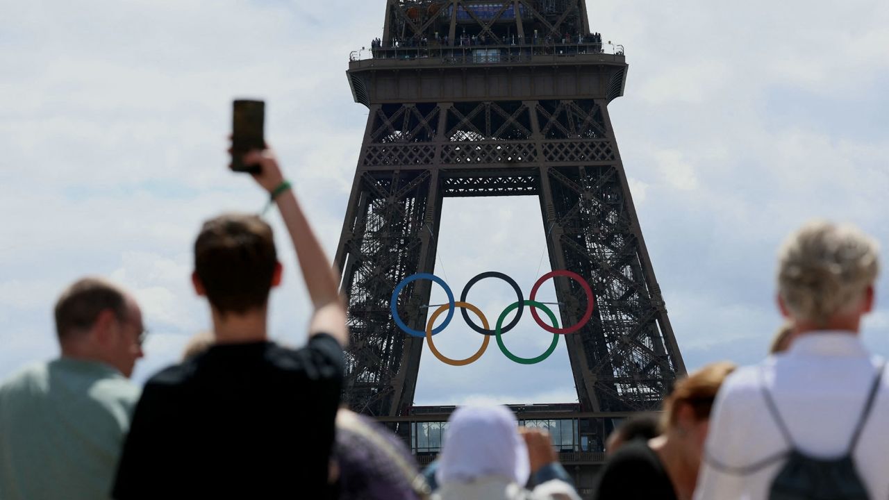 Visitors look at The Eiffel Tower adorned with The Olympic Rings ahead of the 2024 Olympic Games in Paris on July 16, 2024.