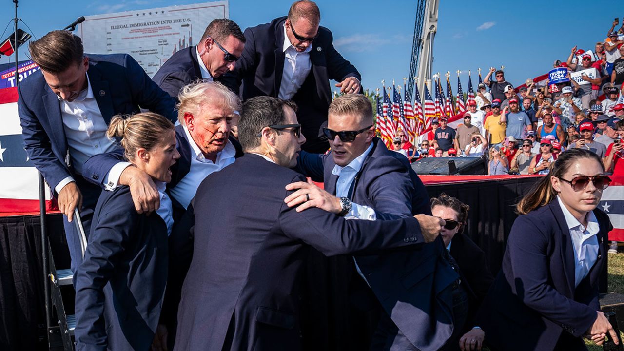 Butler, PA - July 13 : U.S. Secret Service agents remove Republican presidential candidate former president Donald Trump from the stage with blood on his face during a campaign rally at Butler Farm Show Inc. in Butler, PA on Saturday, July 13, 2024. Trump later shared that a bullet pierced part of his ear during the assassination attempt. (Photo by Jabin Botsford/The Washington Post via Getty Images)