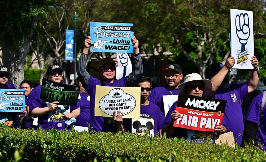 Disney employees hold up signs as they rally outside the main entrance of Disneyland Resort on July 17, 2024, ahead of a planned strike authorization vote. The strike was ultimately averted.