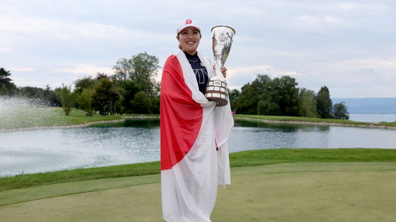 Drapped in a flag of Japan, Japanese golfer Ayaka Furue poses with the Amundi Evian Championship trophy after her dramatic, first-ever major victory on July 14, 2024 in Evian-les-Bains, France.