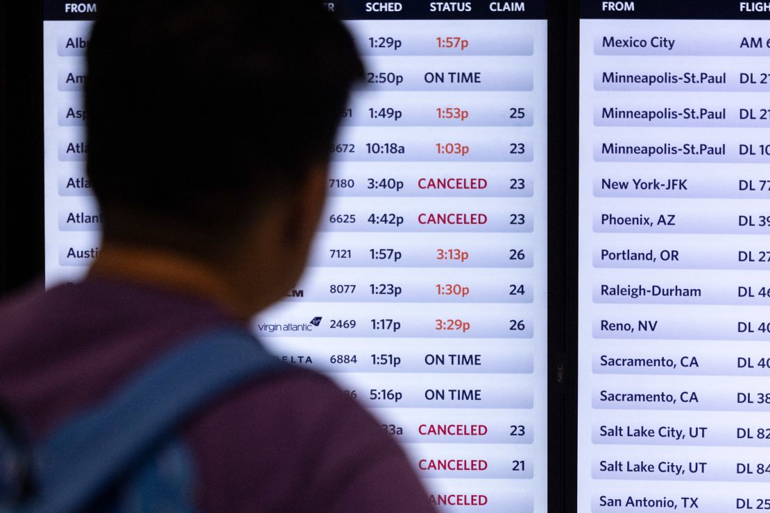 A traveler looks at a screen displaying delayed and canceled flights in Terminal 2, Delta Airlines, at Los Angeles airport, on Friday.