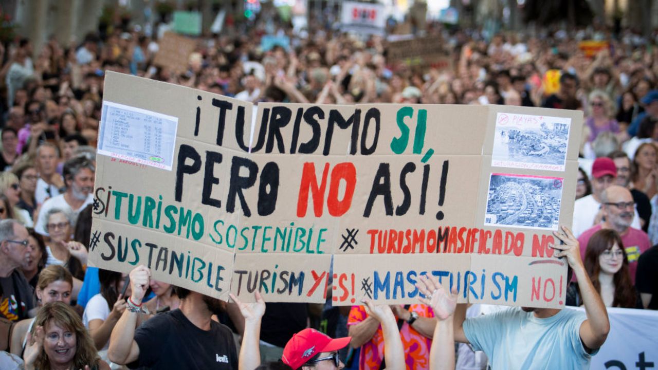 TOPSHOT - People hold a placard which reads as "Tourism yes, but not like this" during a demonstration to protest against overtourism and housing prices on the island of Mallorca in Palma de Mallorca on July 21, 2024. (Photo by JAIME REINA / AFP) (Photo by JAIME REINA/AFP via Getty Images)