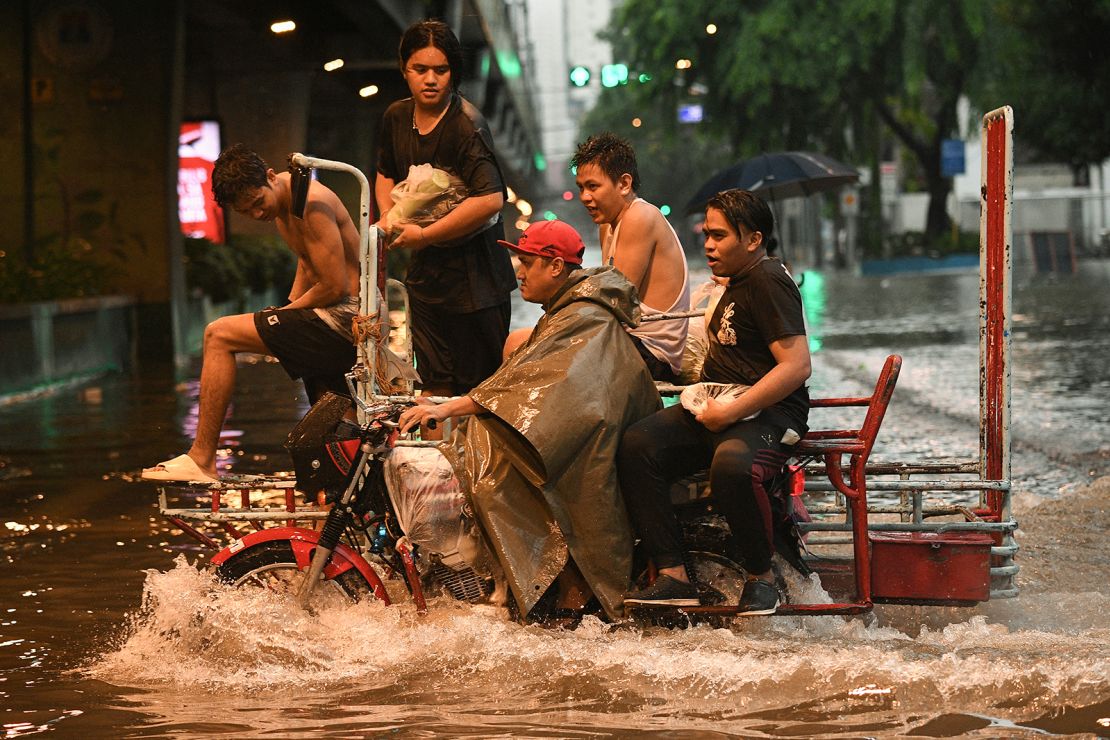 Motorists cross a flooded street in Manila on July 24, 2024 amid heavy rains brought by Typhoon Gaemi.