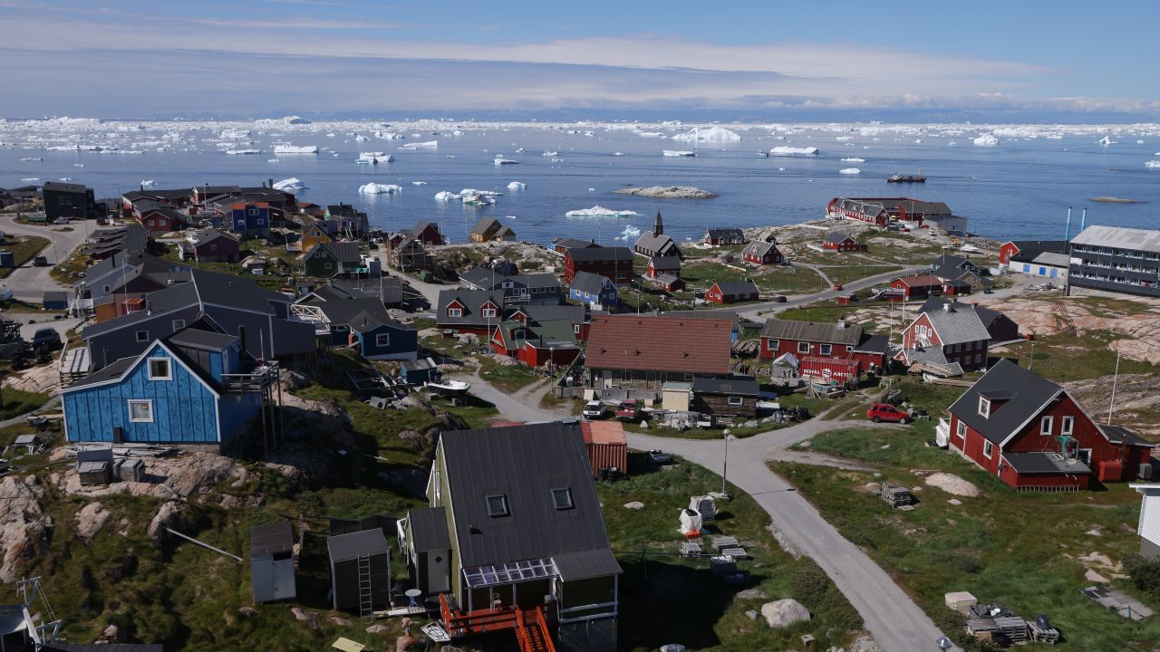 Houses stand as icebergs drift by in Disko Bay on July 15, 2024 in Ilulissat, Greenland. Greenlandic authorities are seeking to improve the territory's infrastructure for tourism. Ilulissat is among the main tourist destinations in Greenland.