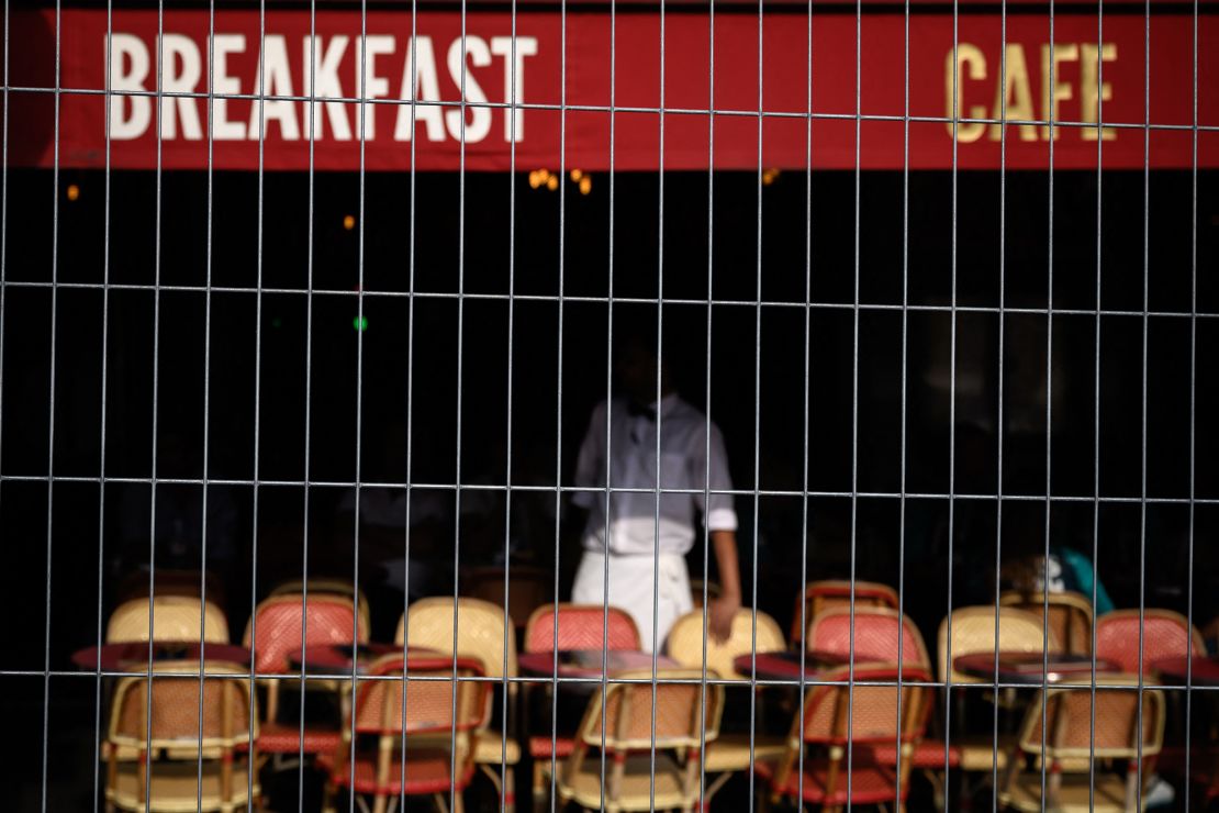 Un camarero en la terraza de un café detrás de unas vallas junto a la Torre Eiffel, antes de los Juegos Olímpicos de París 2024, el 24 de julio.