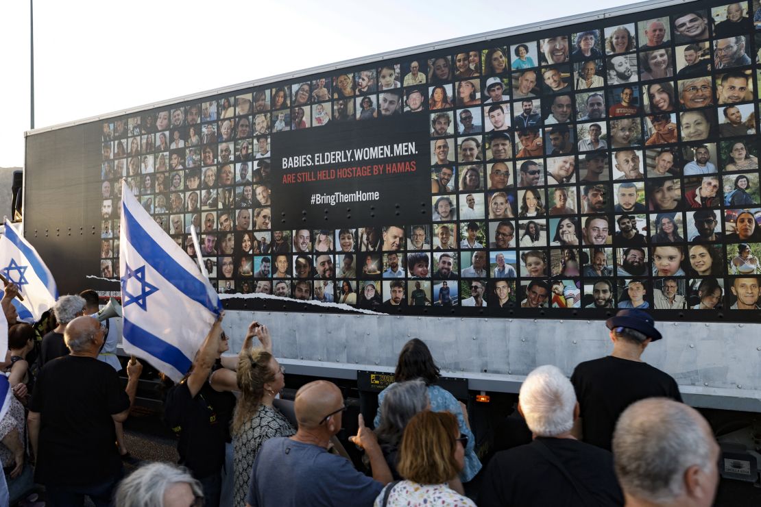 People stand near a wall covered with pictures of Israeli hostages held by Palestinian Hamas militants in the Gaza Strip since the October 7 attacks, during a demonstration against the Israeli government, in the northern Israel city of Karmiel on July 25.