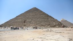 Tourists walk past the pyramids of Khufu, Khafre, and Menkaure on July 21, 2024 in Giza, Egypt.