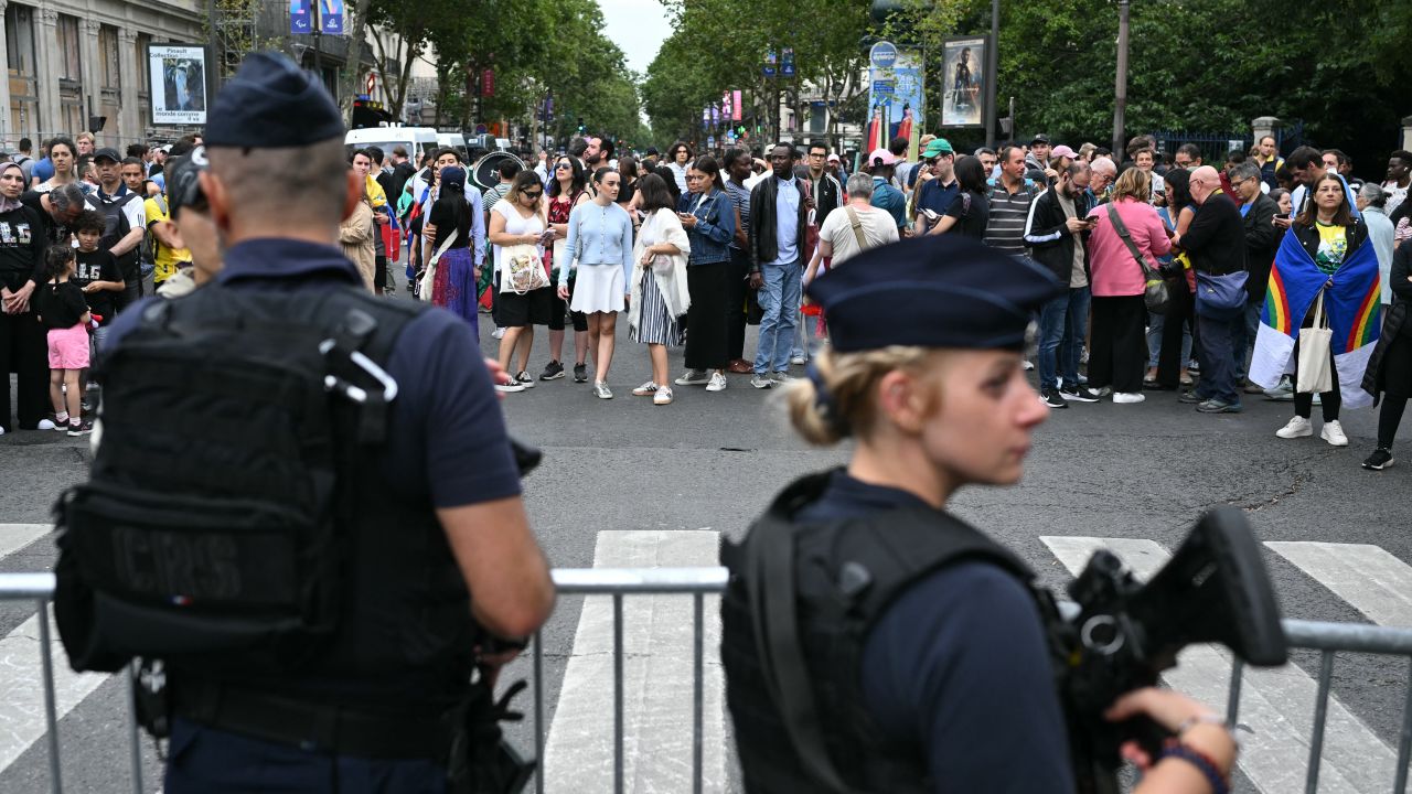 French national police officers stand guard as people queue outside the security perimeter while arriving to attend the opening ceremony of the Paris 2024 Olympic Games in Paris on July 26, 2024. (Photo by Natalia KOLESNIKOVA / AFP) (Photo by NATALIA KOLESNIKOVA/AFP via Getty Images)