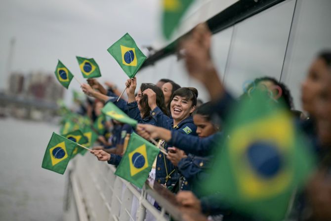 Brazilian athletes wave flags as they travel along the Seine River.