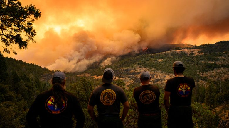 Firefighters watch as flames and smoke move through a valley in the Forest Ranch area of Butte County as the Park Fire continues to burn near Chico, California, on July 26, 2024. More than 1,150 personnel are deployed to fight the blaze, and more than 3,500 people have been forced to flee their homes, according to the California Department of Forestry and Fire Protection.