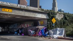 A homeless person stands next to an encampment in Skid Row in downtown Los Angeles, California, on Friday.