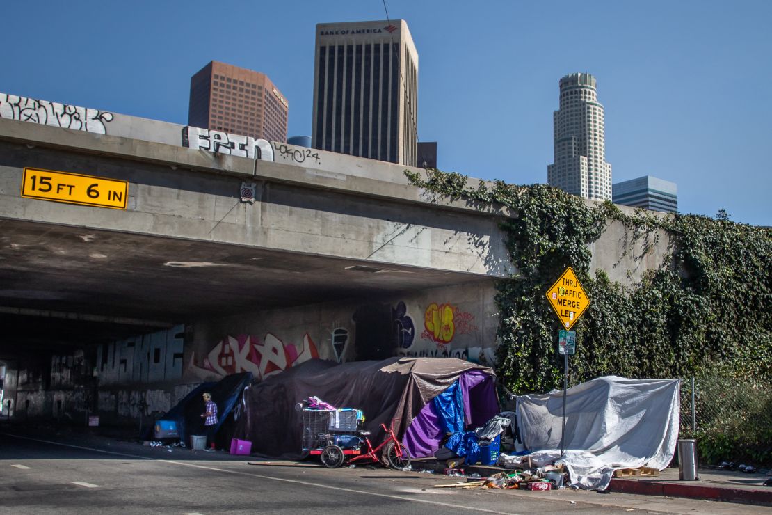 A homeless person stands next to an encampment in Skid Row in downtown Los Angeles on Friday