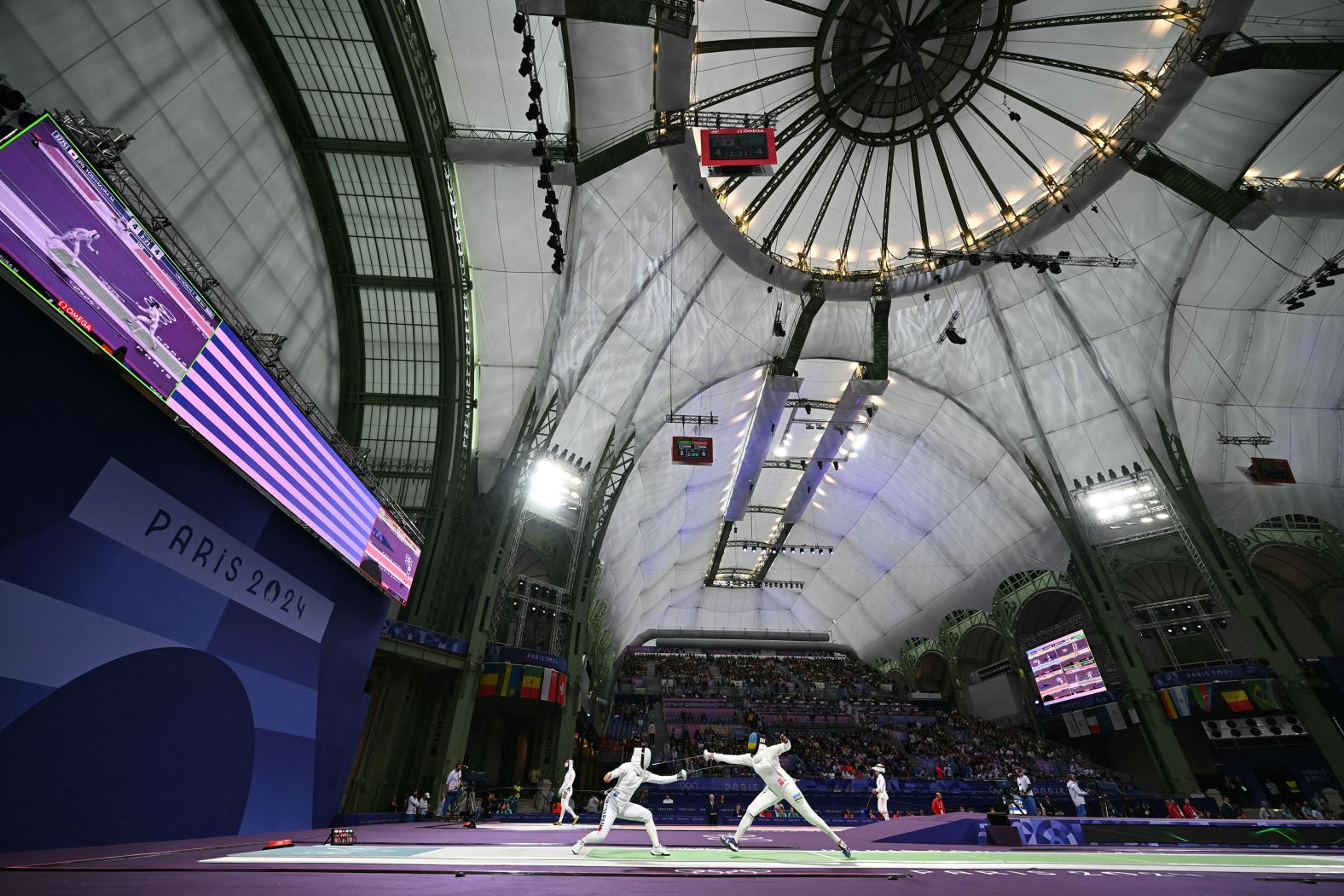 Japanese fencer Miho Yoshimura, left, competes against Rwanda’s Tufaha Uwihoreye in an épée round-of-64 bout on July 27. The Grand Palais, an exhibition hall and event center located off the Champs-élysées, <a >is the cavernous home to all the fencing competitions</a> at the Paris Olympics.