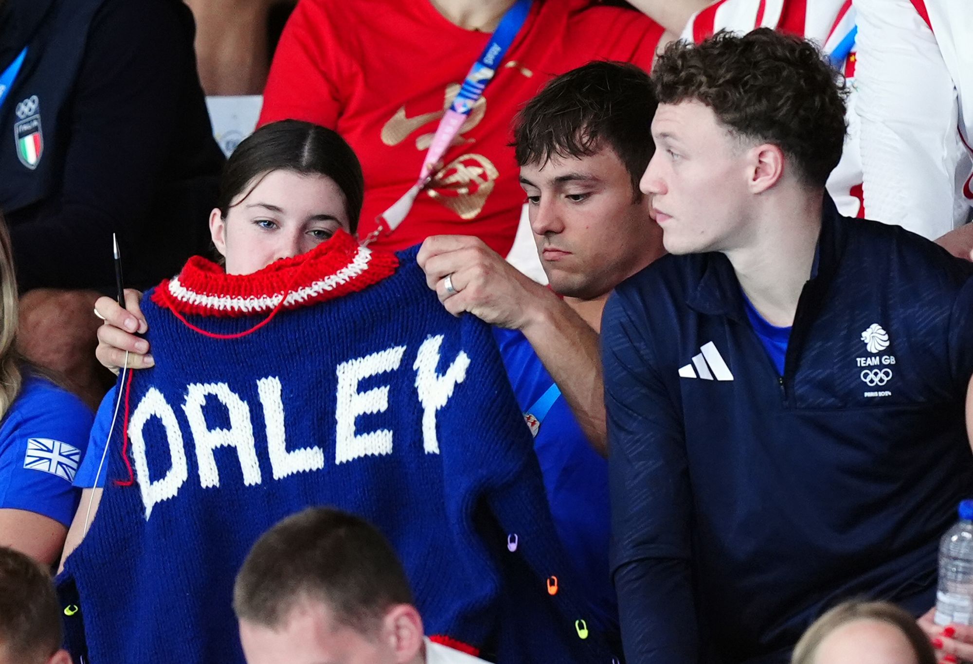 Tom Daley has been spotted knitting several times as he watches the Women's Synchronised 3m Springboard Final at the Aquatics Centre.